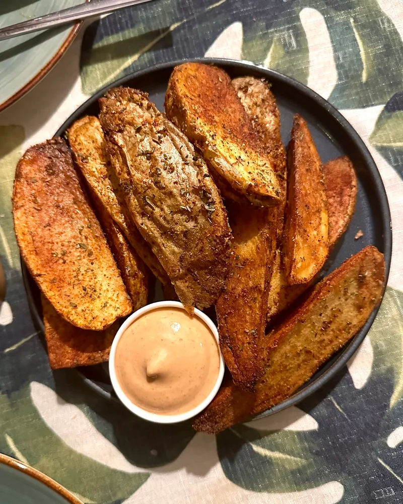 Seasoned potato wedges with a pot of dipping sauce at Kiwi Vegan Cafe