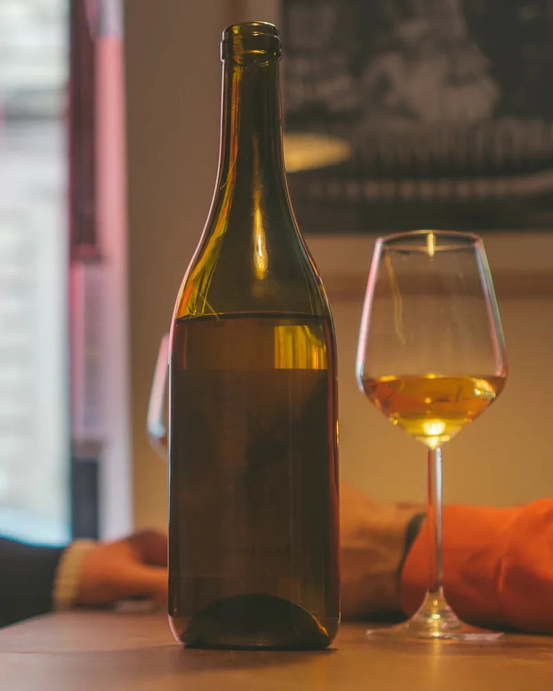 Wine bottle and glass of orange wine on the bar counter at Krebuli Natural Wine Bar