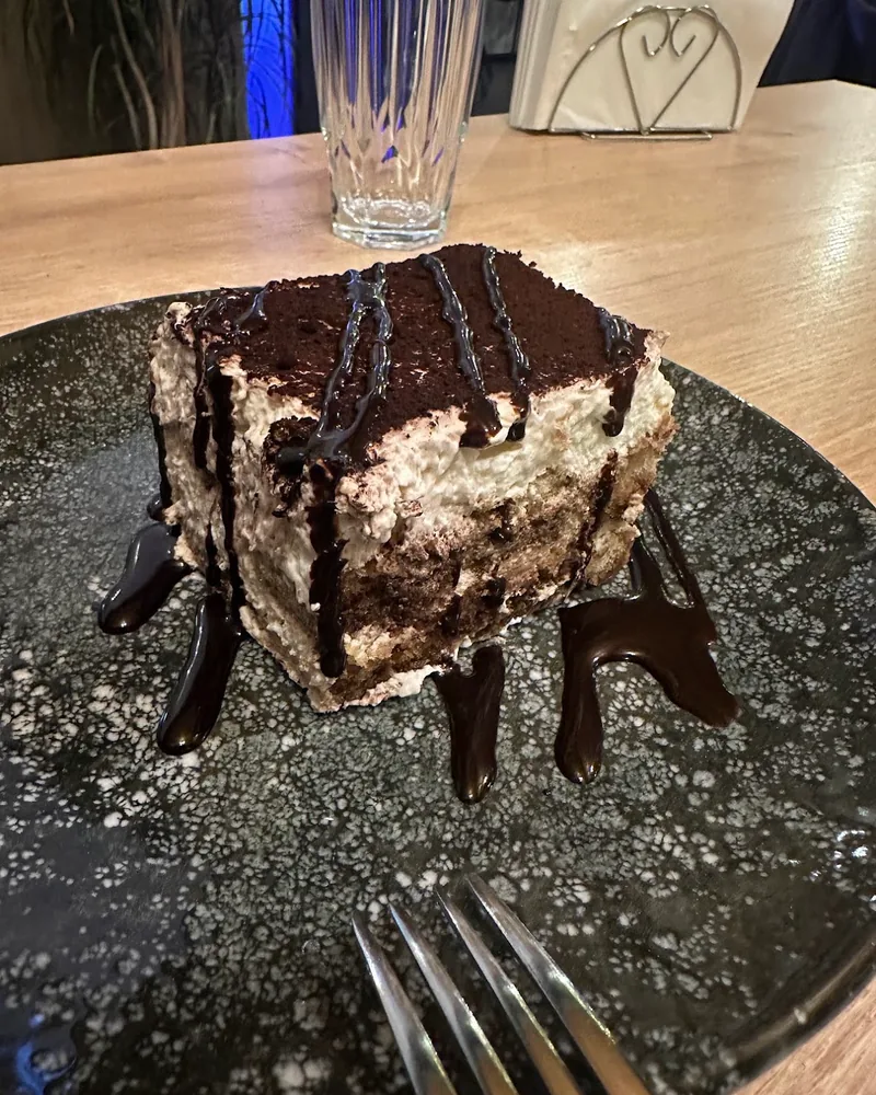 Tiramisu slice drizzled with chocolate sauce at La Burrata