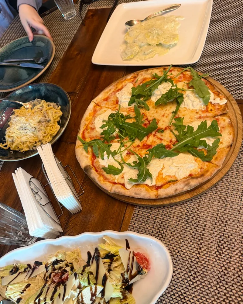 Pizza with burrata and arugula on a wooden board at La Burrata