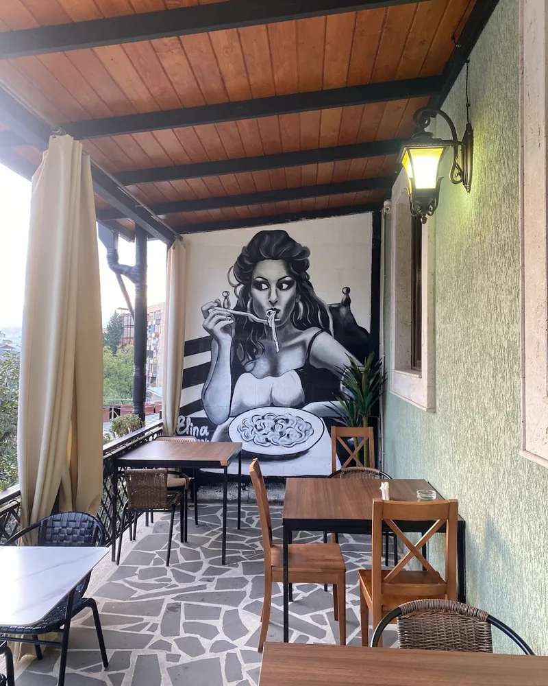 Terrace dining area with wall mural and stone floor at La Burrata