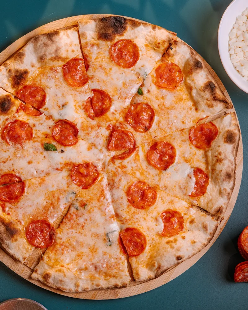Sliced pepperoni pizza on a wooden peel at La Crosta Pizzeria