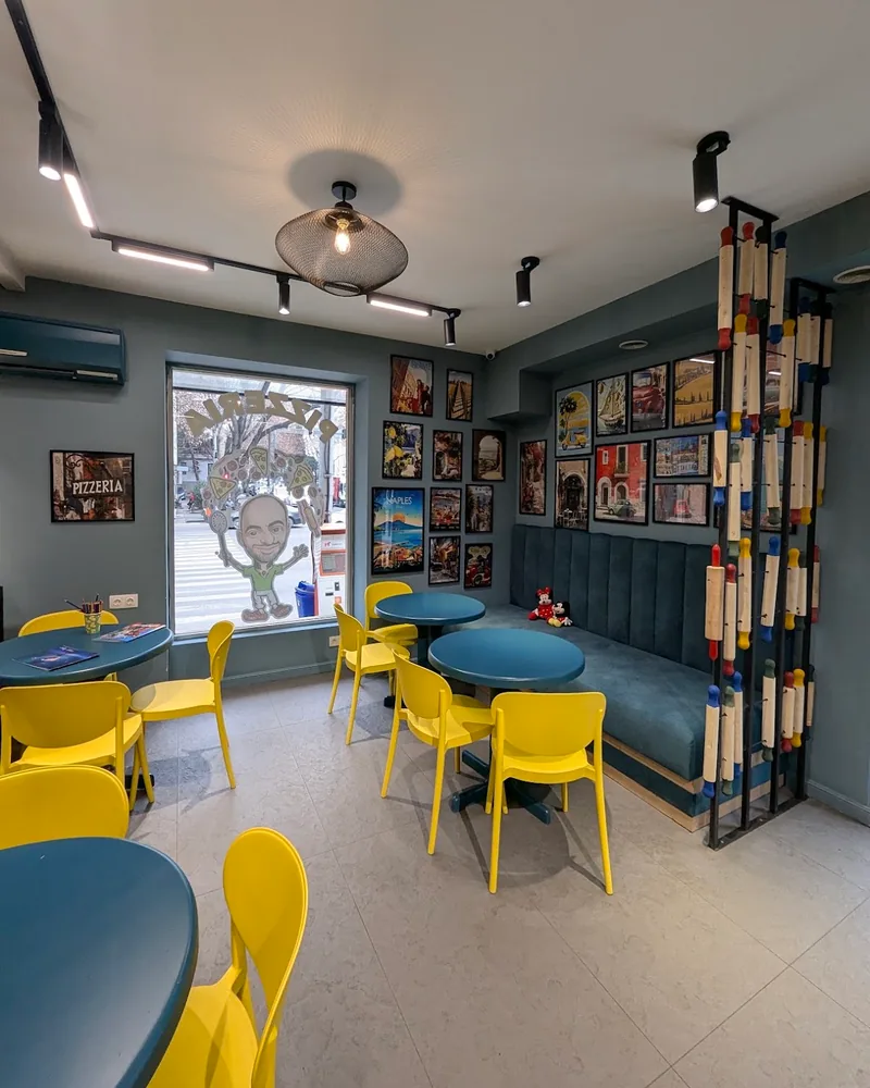 Dining area with yellow chairs and blue banquette at La Crosta Pizzeria