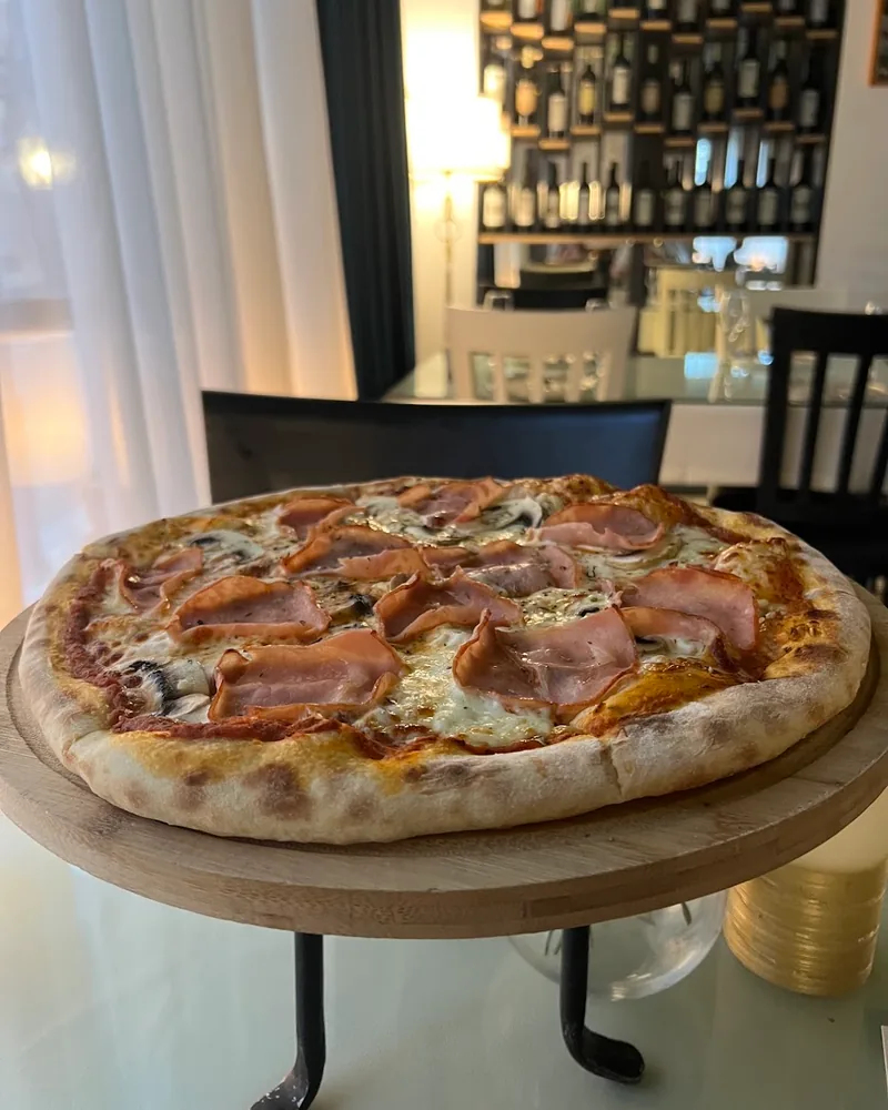 Pizza with prosciutto and mushrooms on a raised wooden stand at Lavera