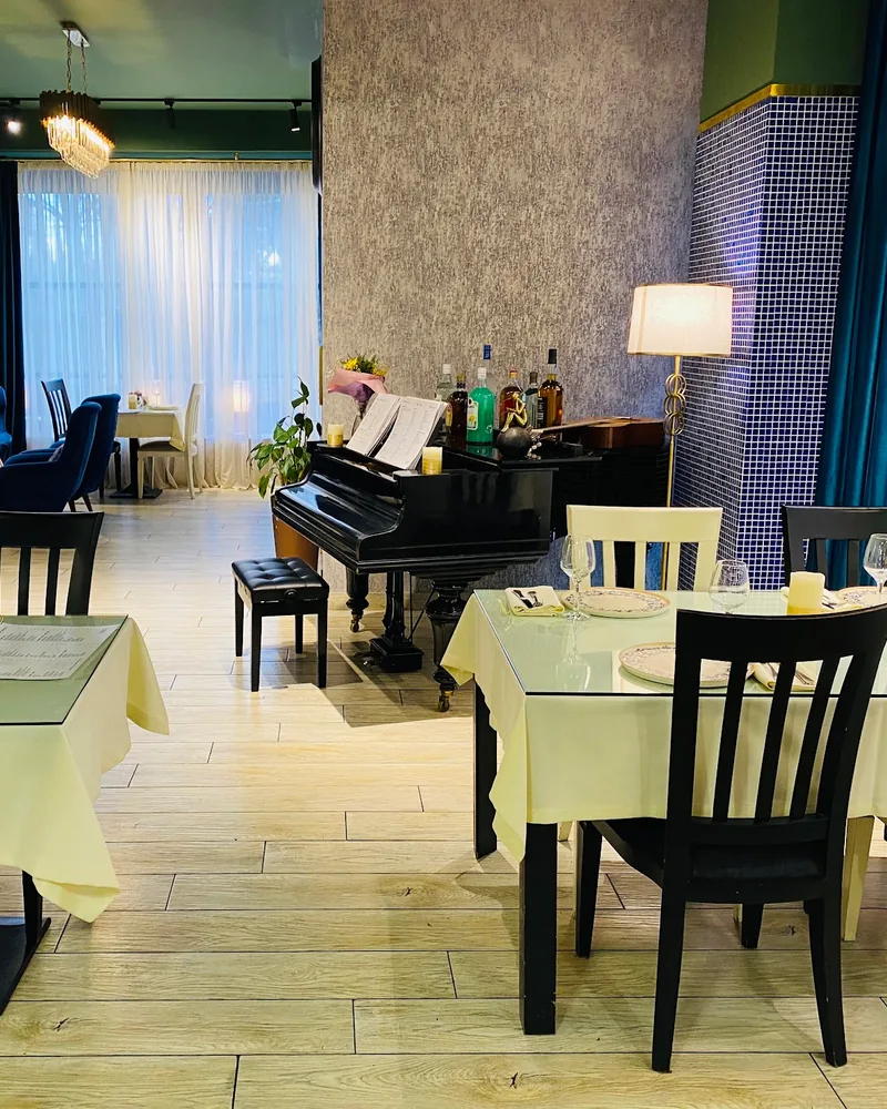 Dining room with piano and set tables at Lavera