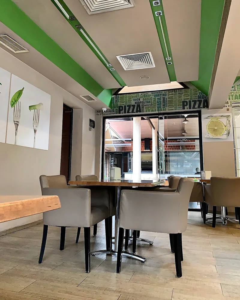 Dining area with modern chairs and green accented ceiling at Lazuri Bakery
