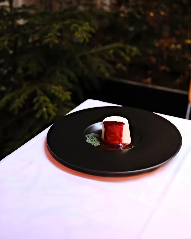 Panna cotta with berry sauce on a black plate at Le Marais de Mome