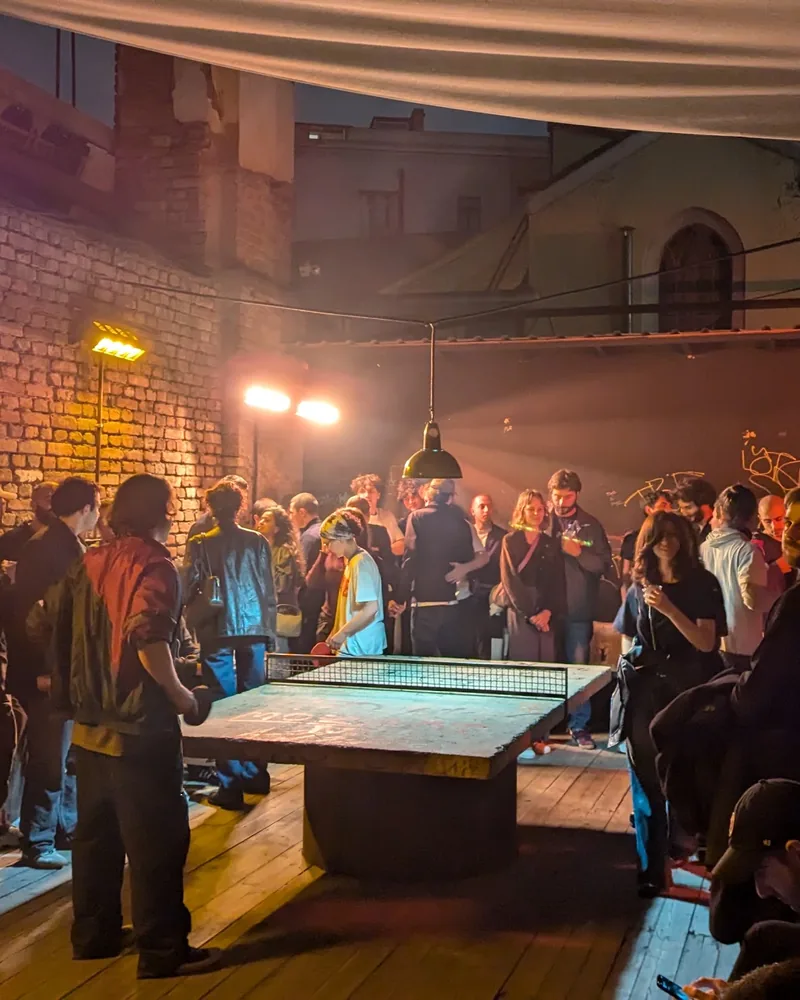 Outdoor courtyard with ping pong table and crowd at Left Bank