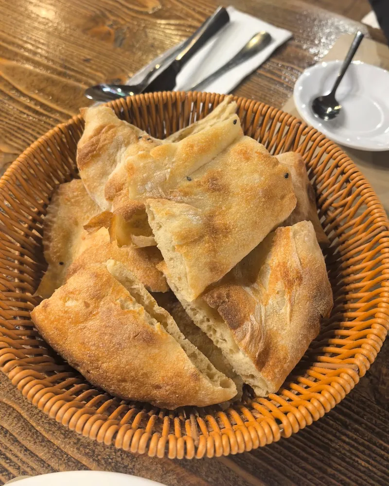 Fresh flatbread pieces in a woven basket at Lezz-Et