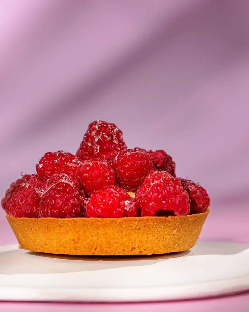 Raspberry tartlet on a white plate at Lika