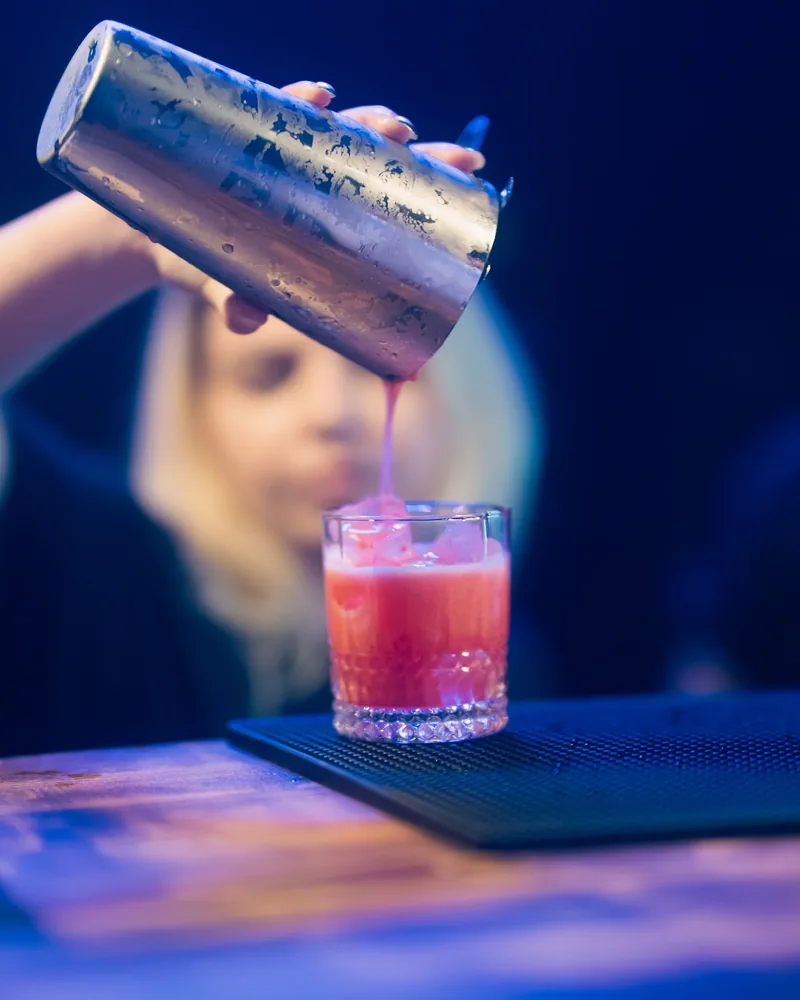 Pink cocktail poured from a shaker into a rocks glass at Looper's Bar