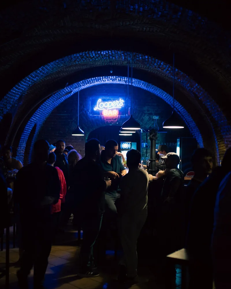 Vaulted brick cellar bar with neon sign at Looper's Bar