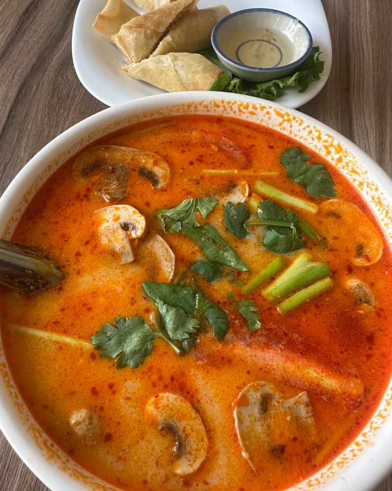 Bowl of tom yum soup with mushrooms and herbs at Lumos Thai Restaurant