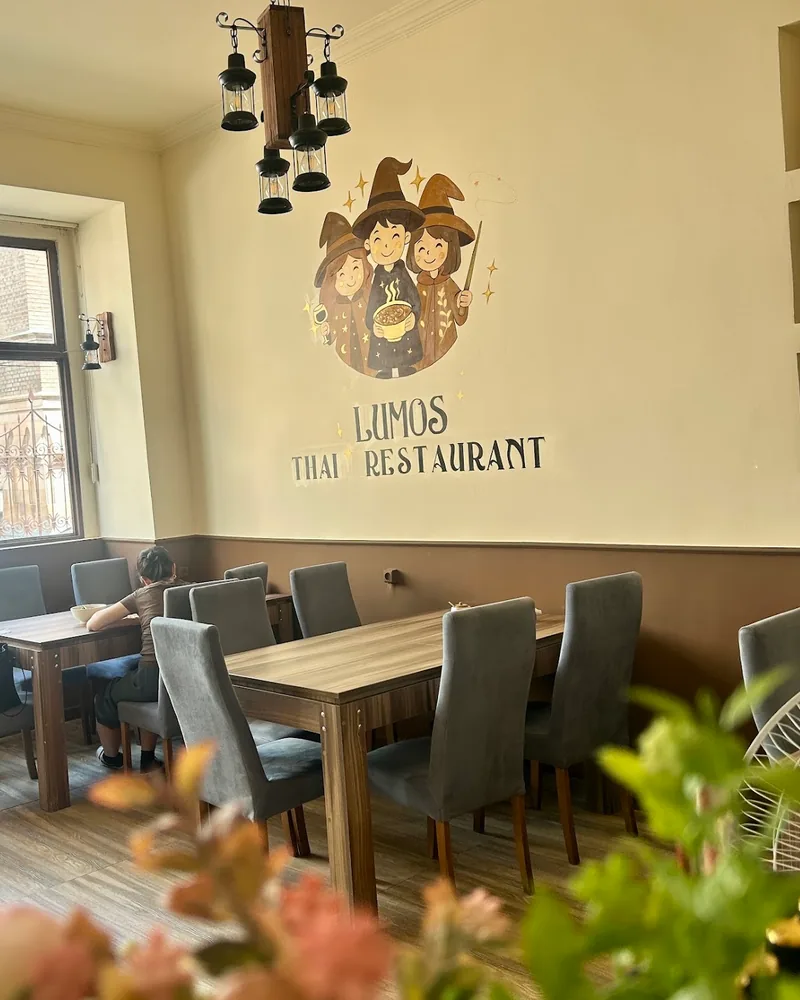 Dining area with mural and wooden tables at Lumos Thai Restaurant