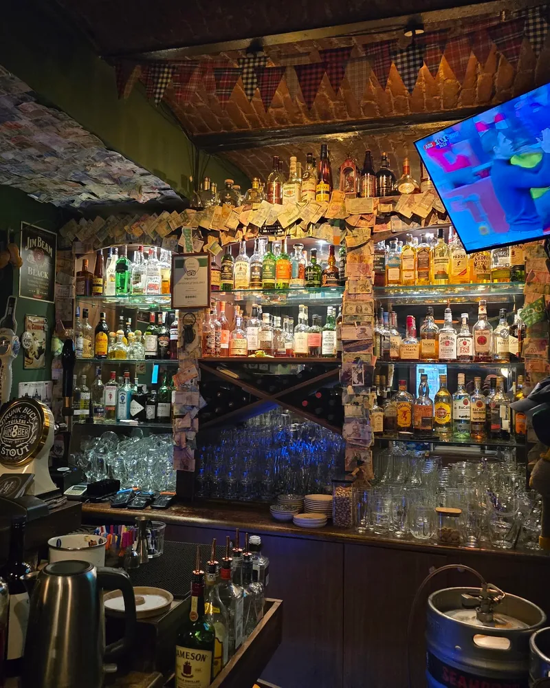 Back bar bottle shelves with banknotes and tv at MacLaren's Irish Pub