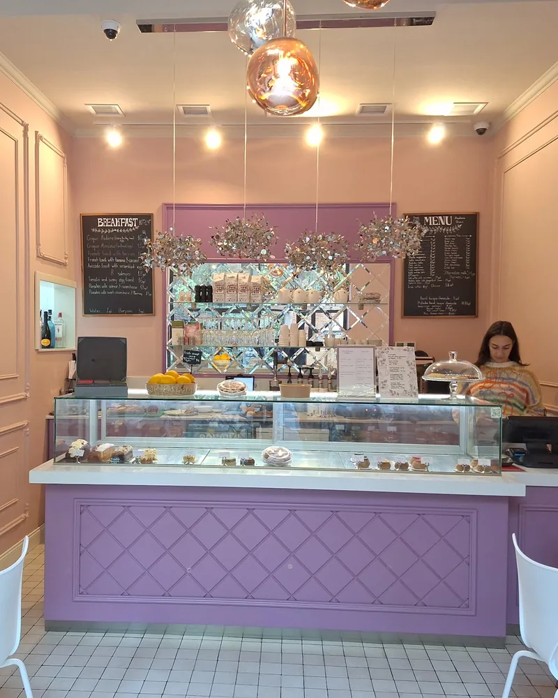 Pink patisserie interior with the pastry counter and seating at Madame Choux