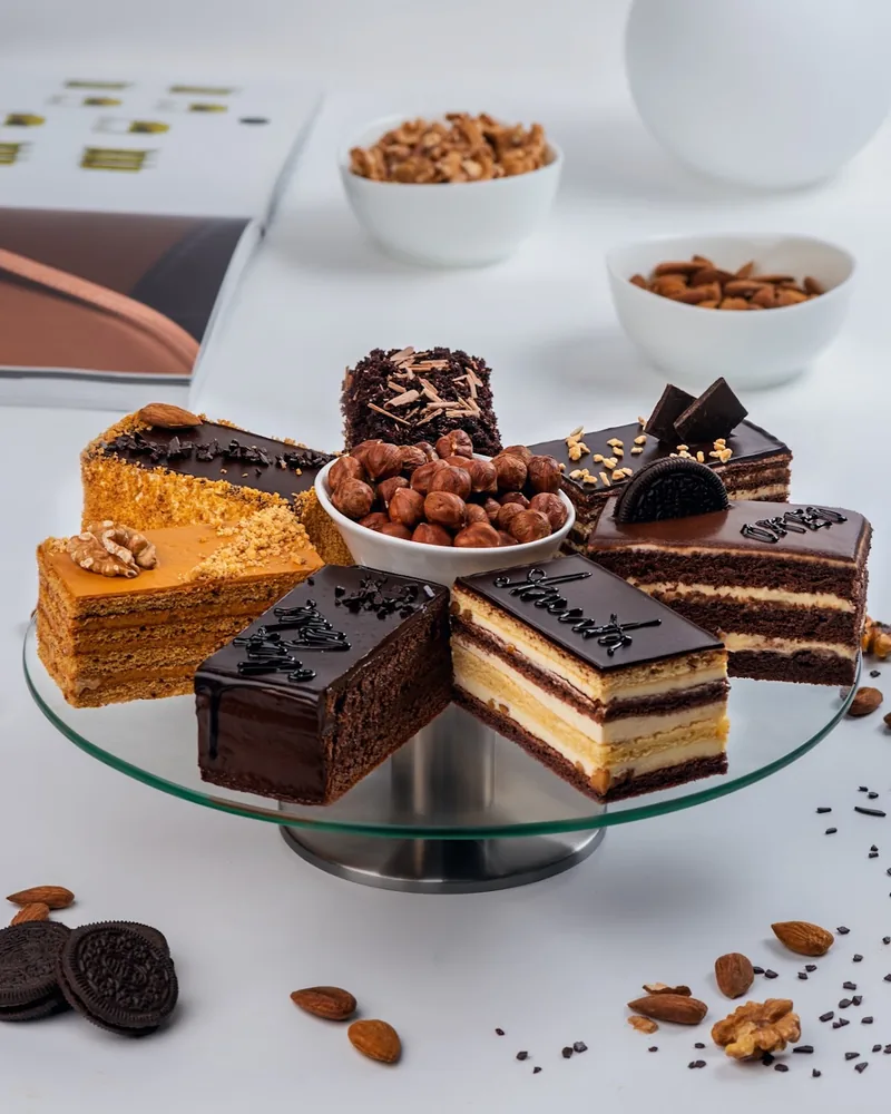 Assorted cake slices on a glass cake stand at Madart