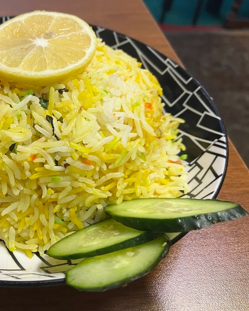 Biryani rice with a lemon slice and cucumber garnish at Masha Allah