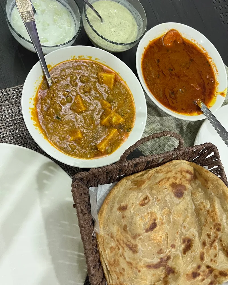 Indian curry dishes with paratha and raita at Mashallah Indian Restaurant