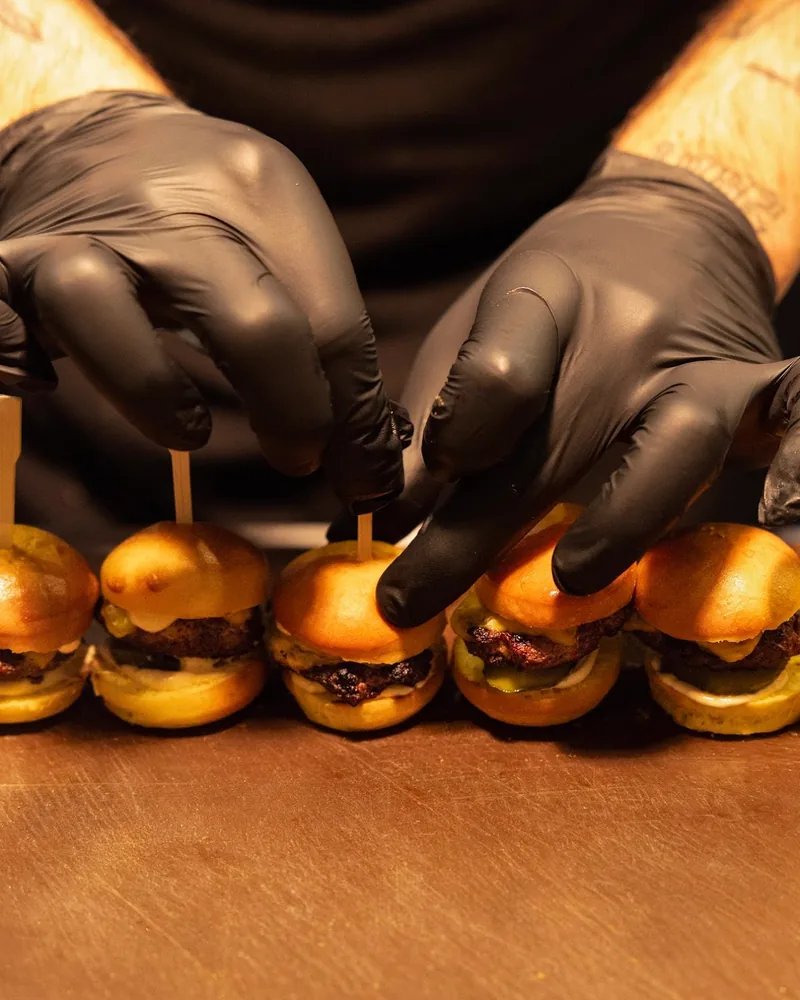 Mini slider burgers prepared by chef in black gloves at Melting Pot