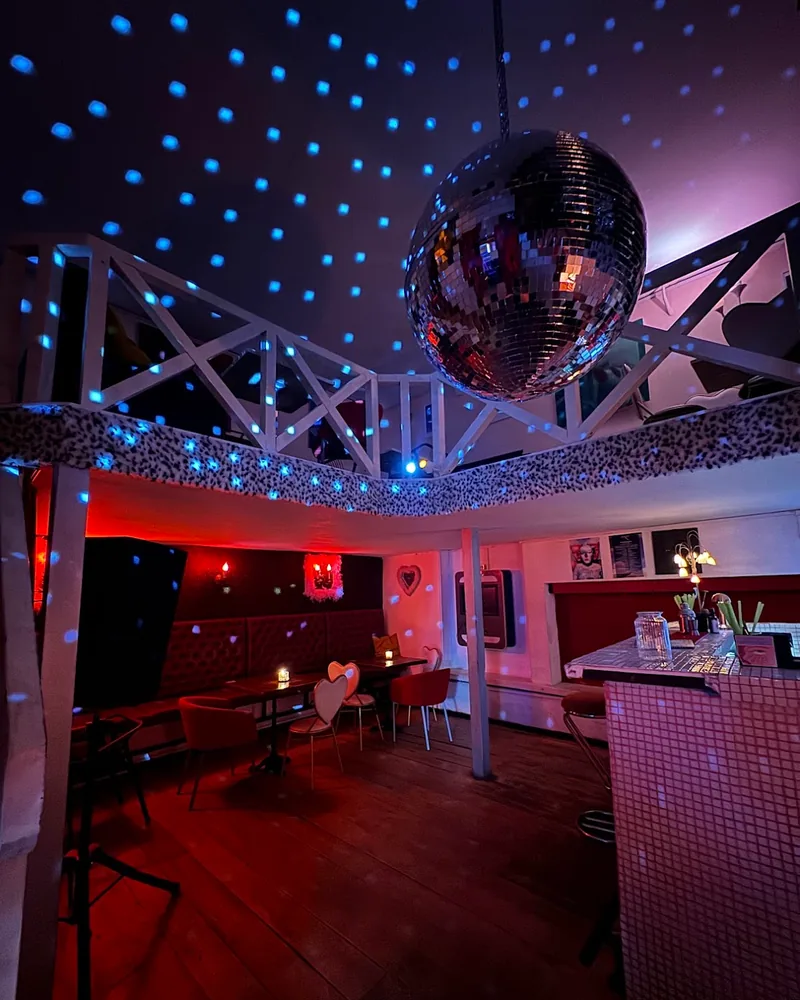 Two-level bar room with a disco ball and blue light dots at Mimosa Bar & Kitchen