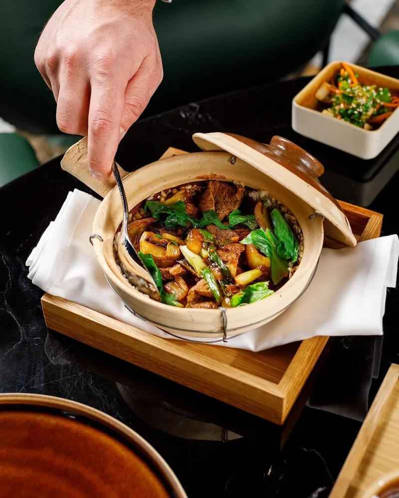 Clay pot rice dish served with beef and greens at Mozaiko