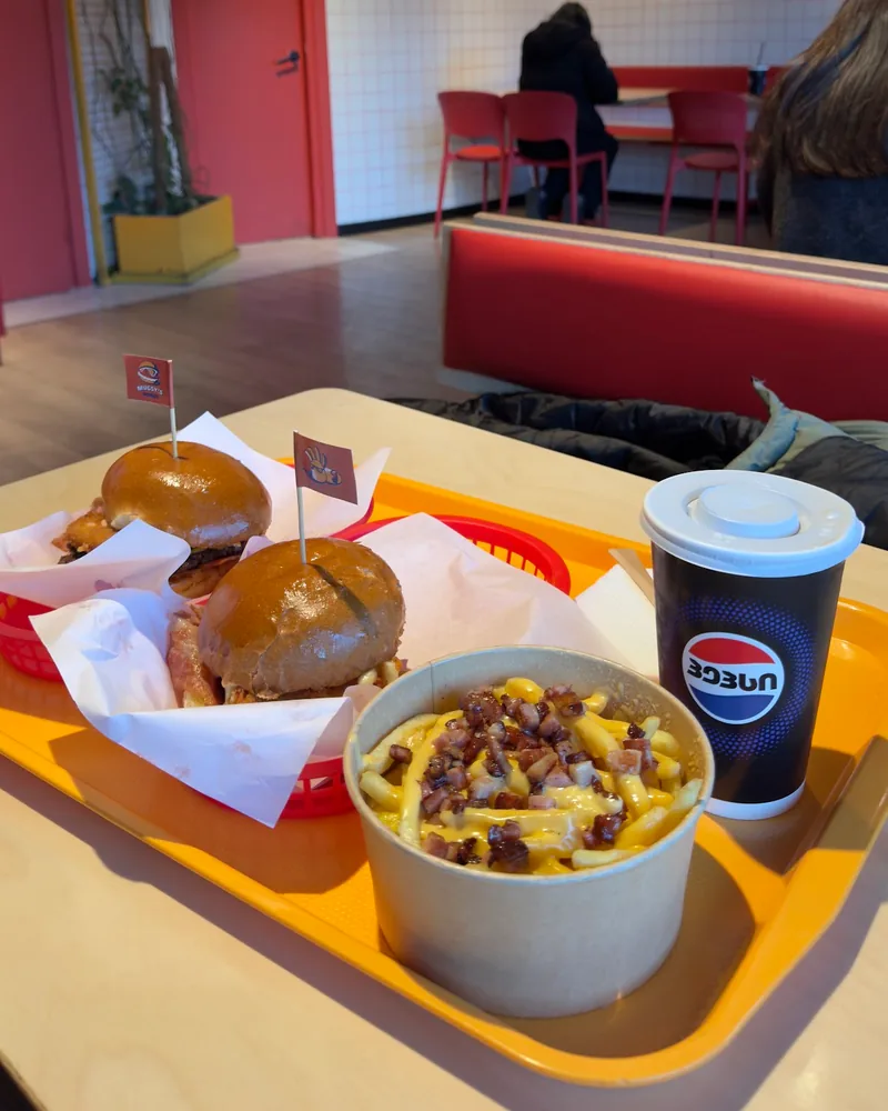 Burgers, loaded fries and a soda cup on a tray at Mugsy's Burger