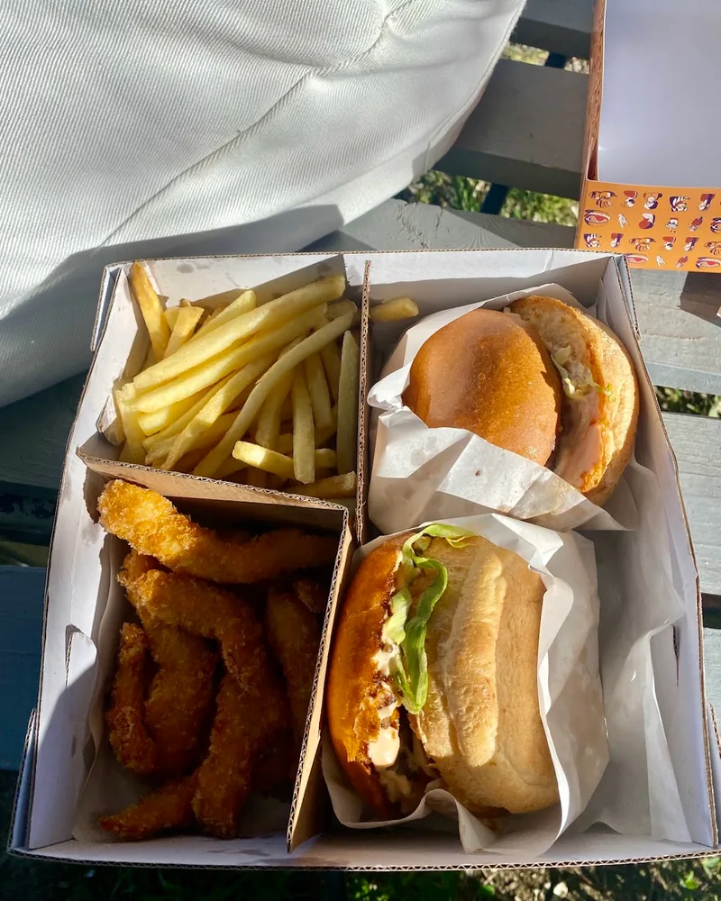 Takeout box with burgers, fries and fried chicken strips at Mugsy's Burger