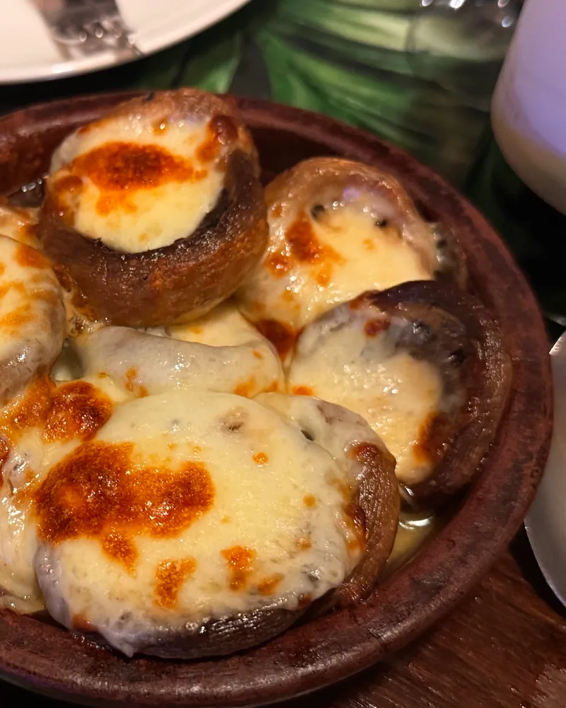 Mushrooms baked with cheese in a clay dish at Muse