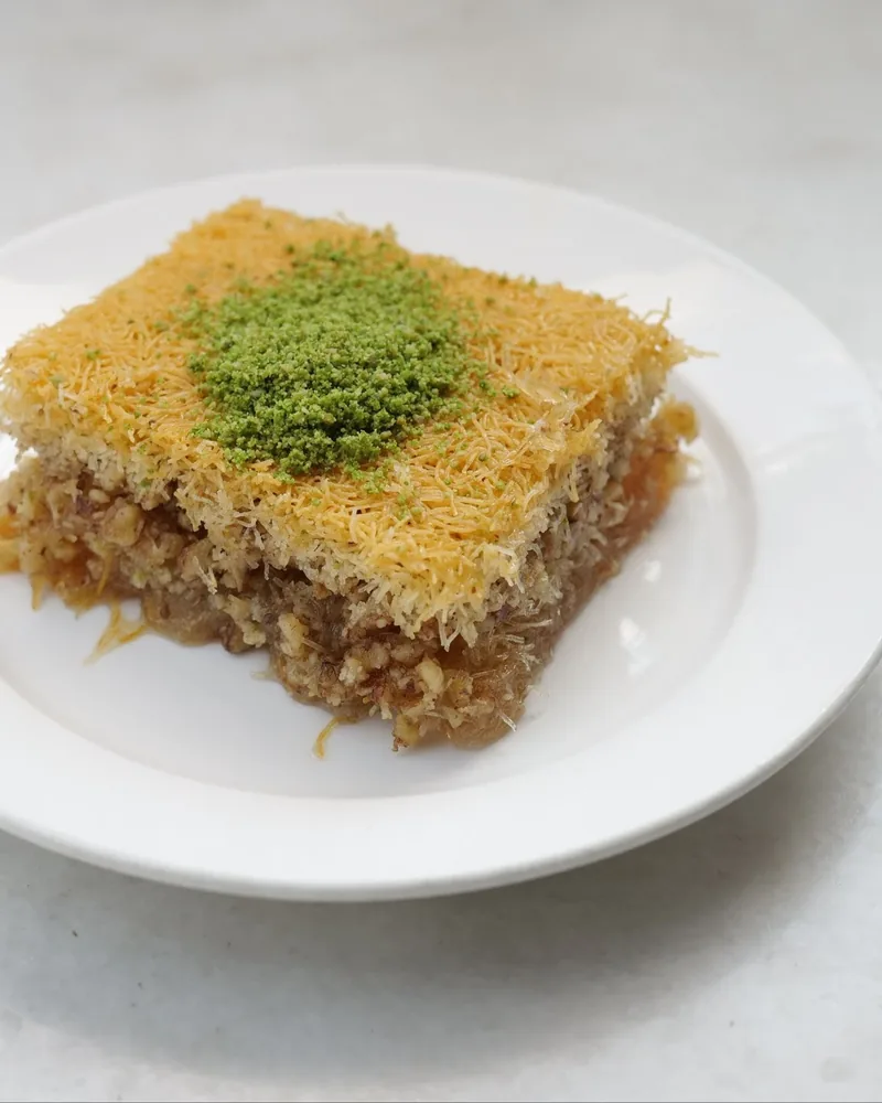 Kadayif pastry with ground pistachio on a white plate at Nasimi