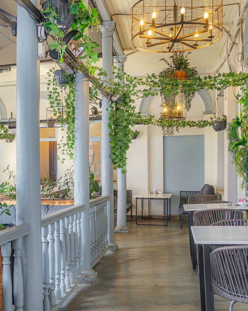 Covered terrace with wooden balustrade and hanging plants at Nasimi