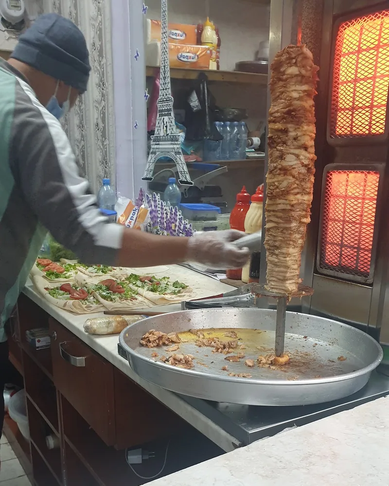 Shawarma spit and prep counter with cook at Nawras Aziz Shawarma