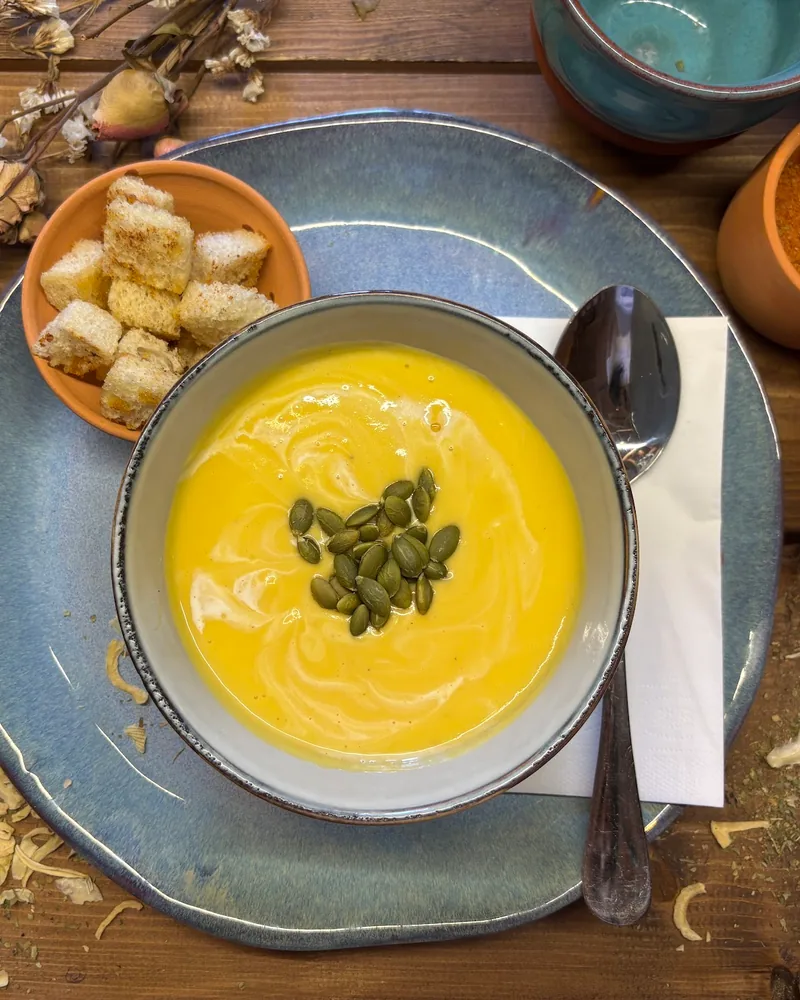 Yellow pumpkin soup topped with pumpkin seeds and croutons at Nilo