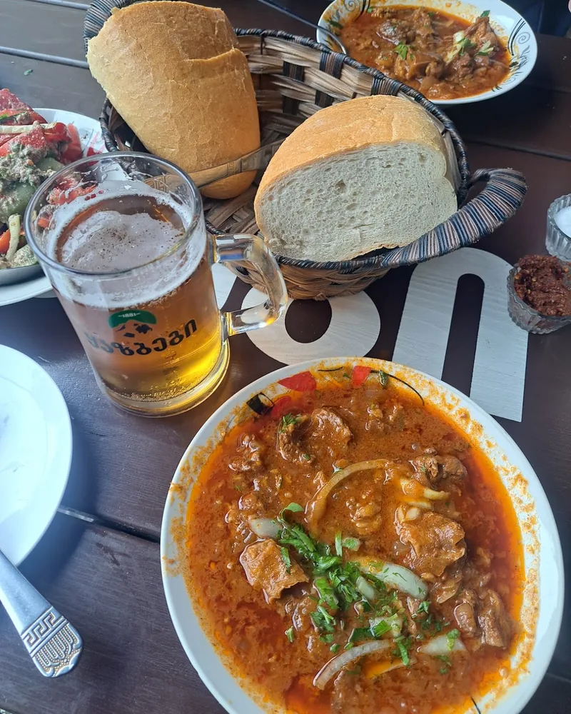 Kharcho stew with bread and beer on a table at Ochamchire
