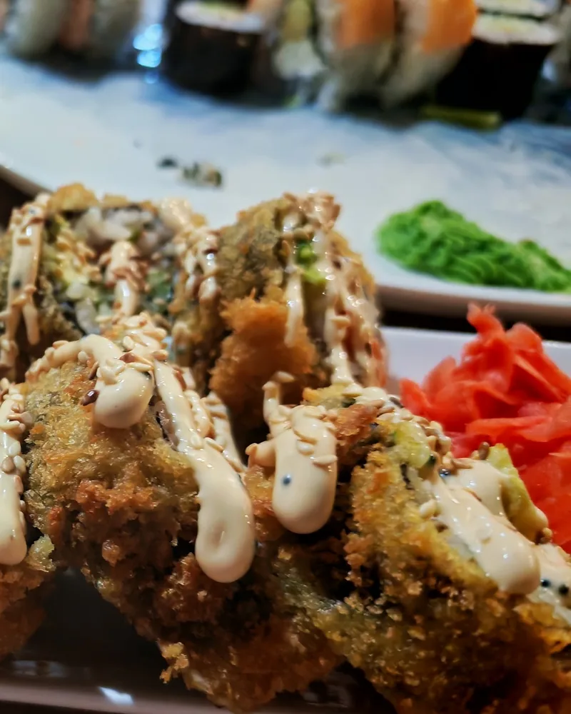 Deep-fried tempura sushi roll drizzled with spicy mayo at Oishi Sushi