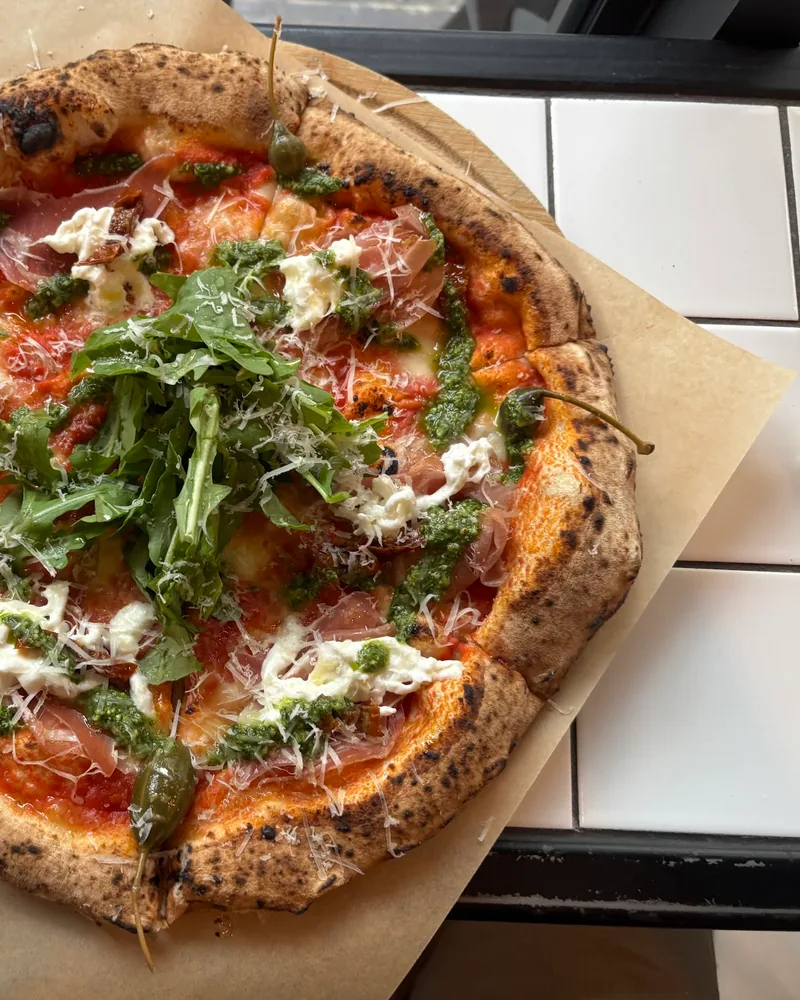 Neapolitan pizza with prosciutto, pesto, and arugula at Olio