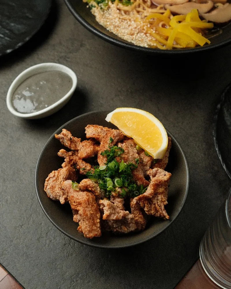 Fried chicken karaage with lemon wedge and scallions at Orbeliani