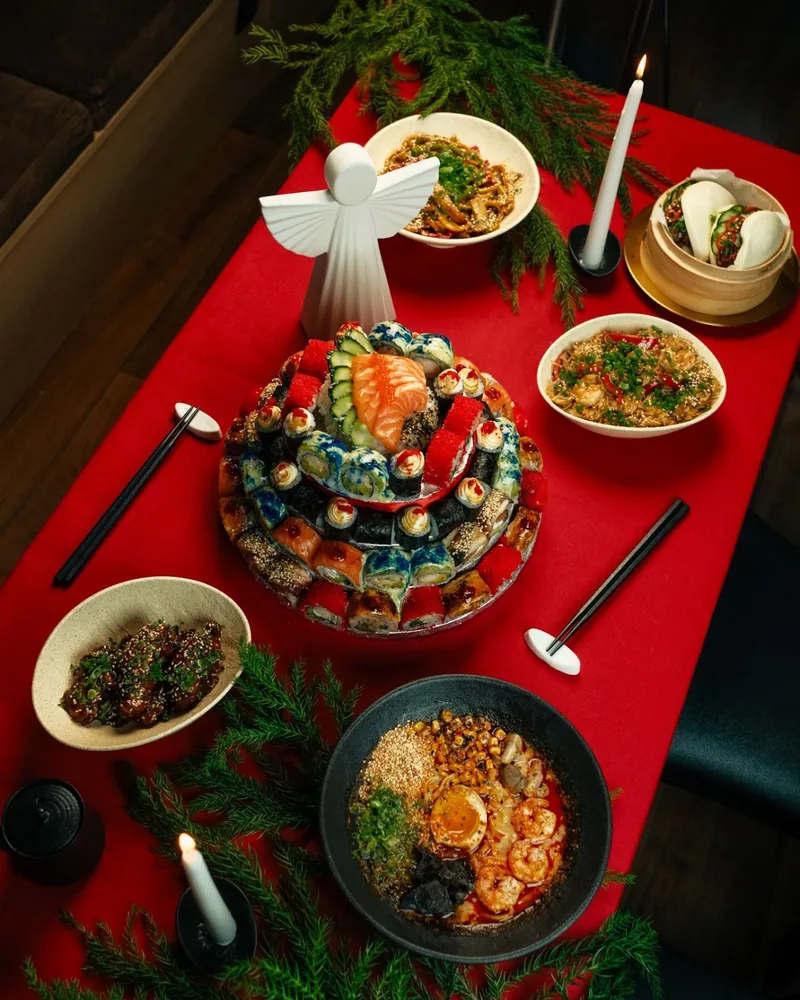 Sushi cake tower with ramen and asian feast on red tablecloth at Orbeliani
