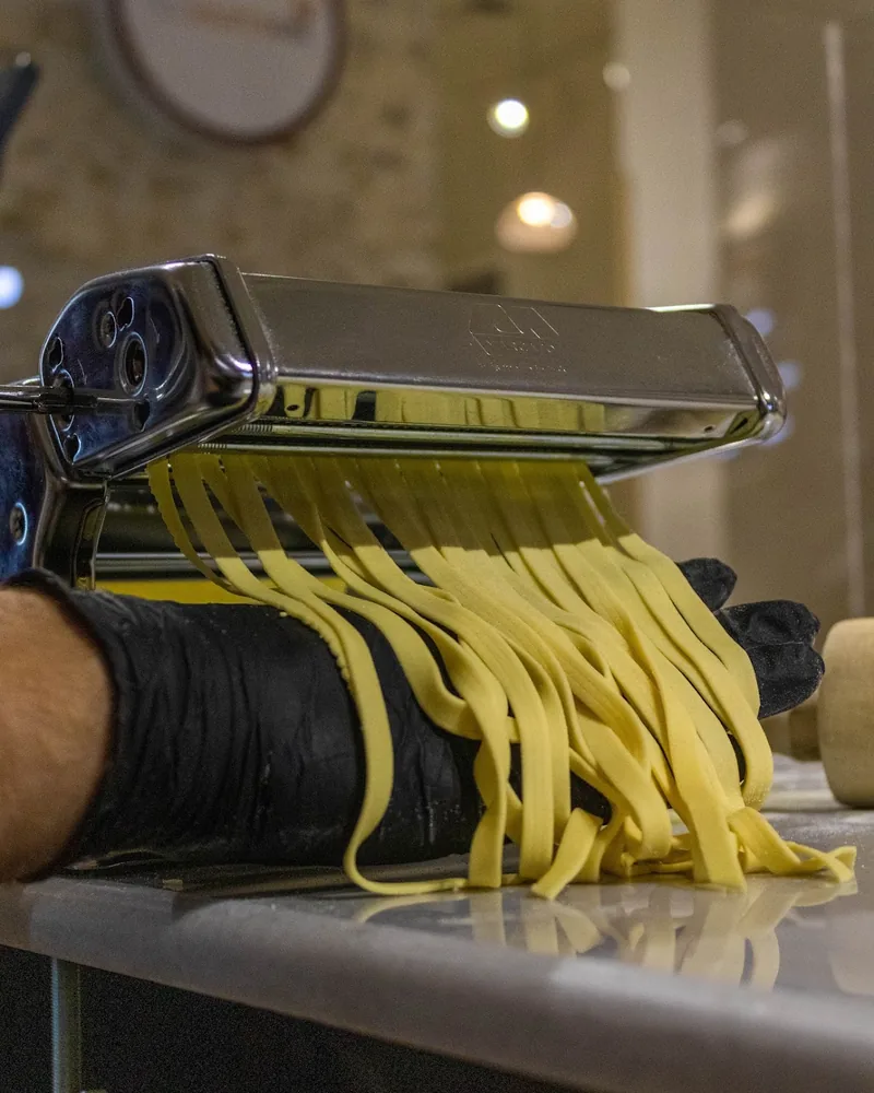 Fresh fettuccine coming out of a pasta roller at Pastachi (Marjanishvili)