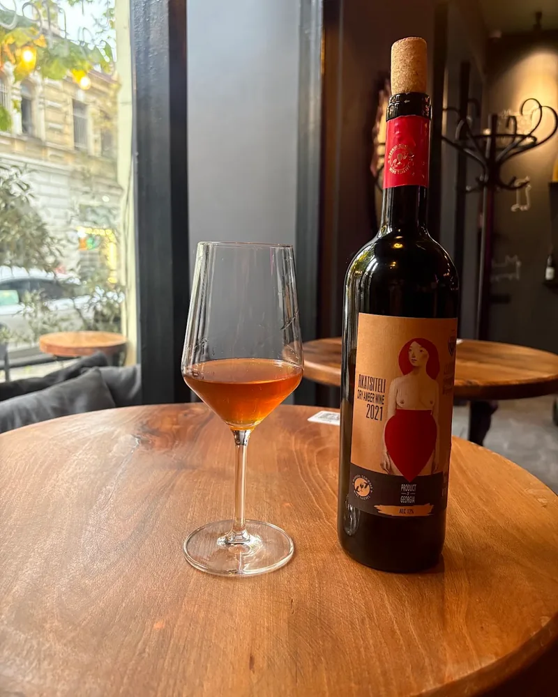 Glass of amber wine beside its bottle at Patara Dzagli