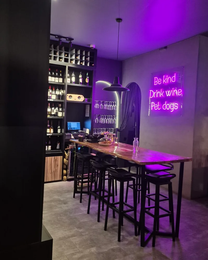 Wine bar seating with a high table and a neon sign at Patara Dzagli