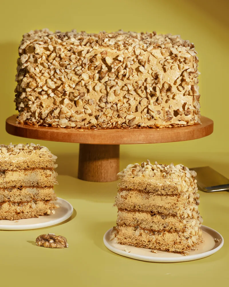 Layered walnut cake with cut slices on small plates at Patisserie Bela (Gldani)