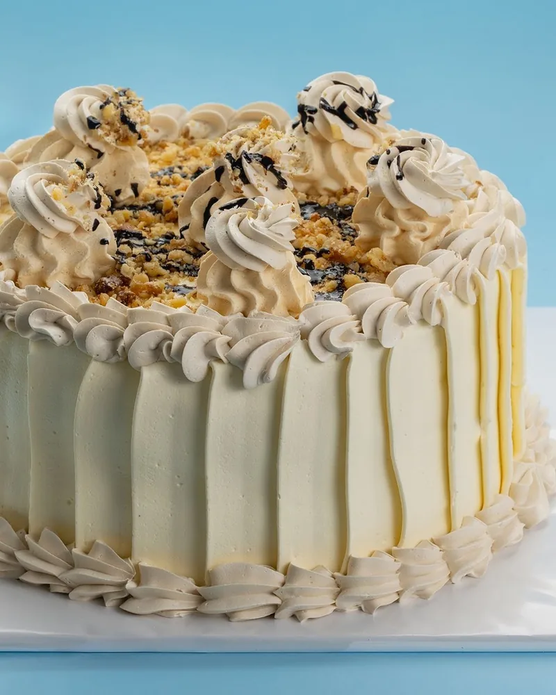 Frosted cake with meringue rosettes and walnuts at Patisserie Bela (Gldani)