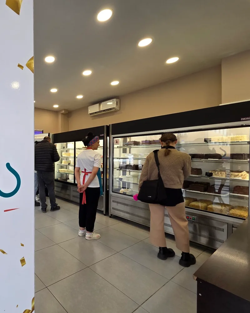 Bakery display fridges with customers and staff at Patisserie Bela (Gldani)