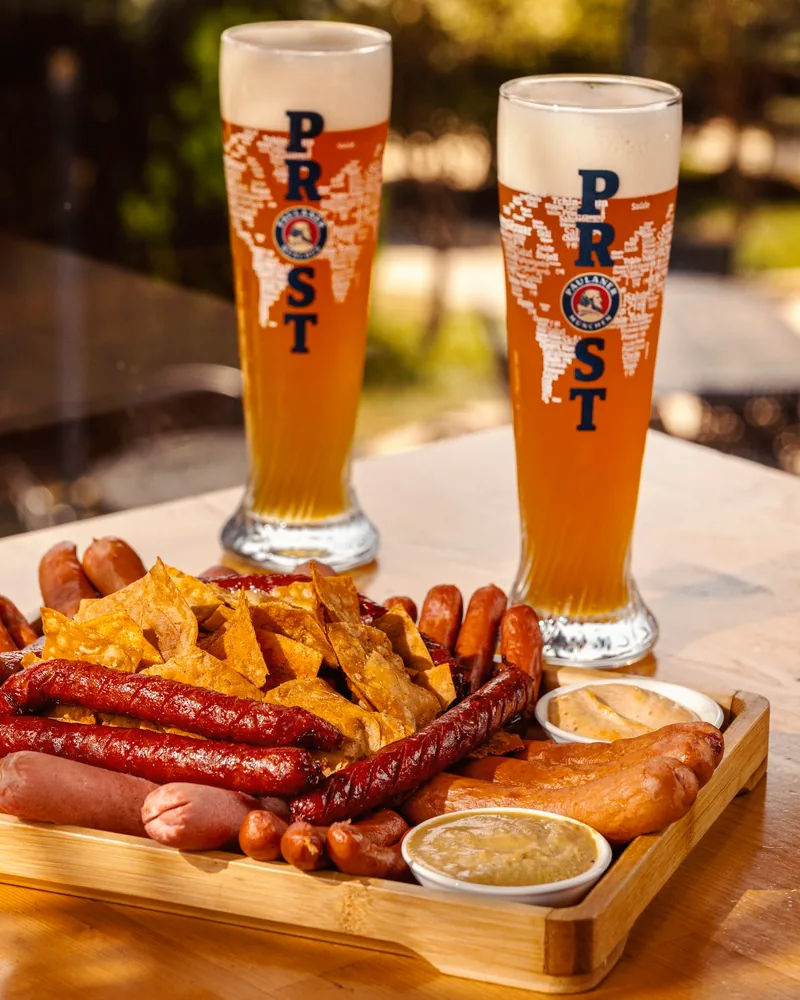 Sausage platter with chips, dips and glasses of wheat beer at Paulaner Beer garden