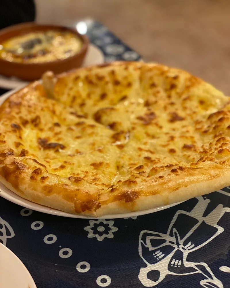 Imeretian khachapuri on a white plate at Pirosmani's Dukani