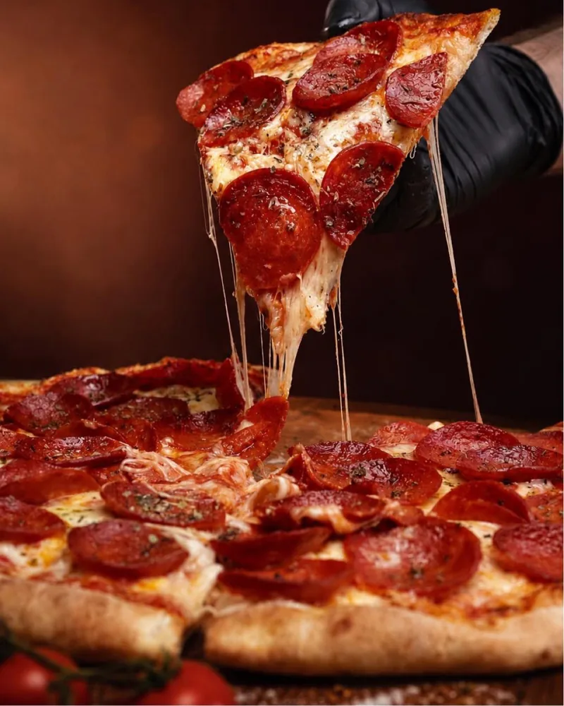 Slice of pepperoni pizza lifted with melted cheese pull at Pizza Dou
