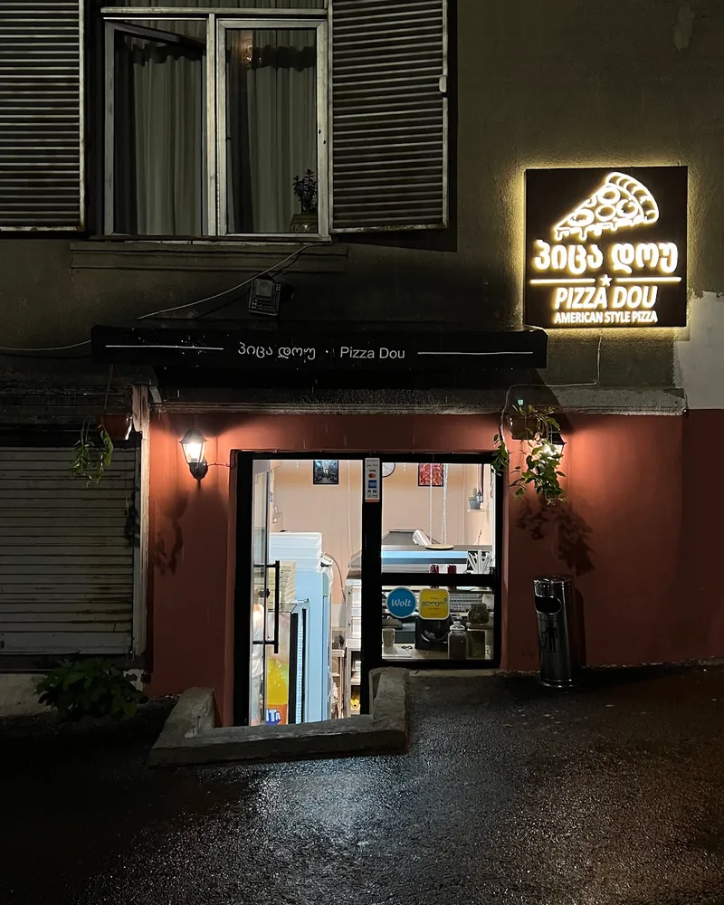 Illuminated storefront and entrance at night at Pizza Dou