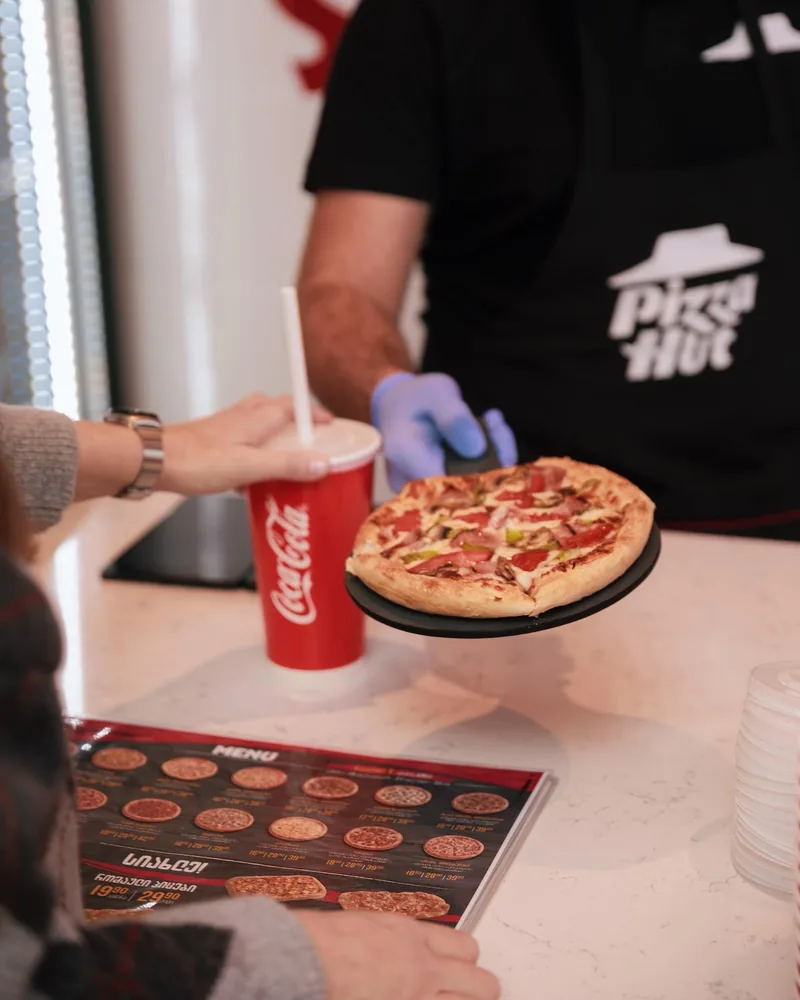 Small pan pizza served on a black paddle at Pizza Hut (Isani)