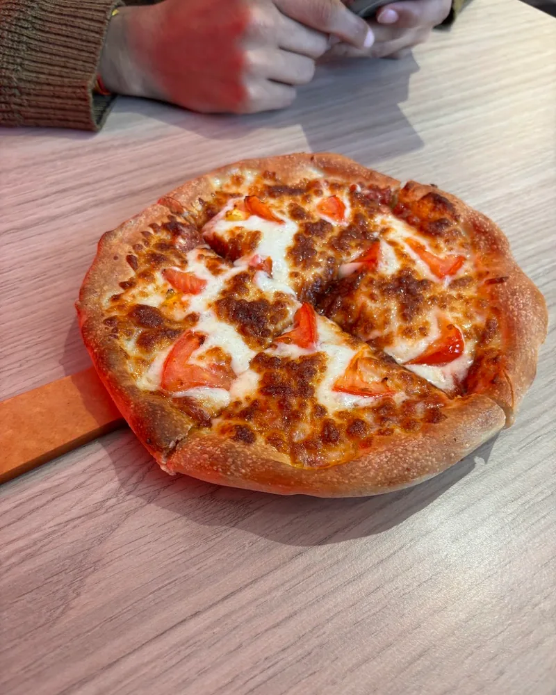 Small cheese and tomato pizza on a wooden peel at Pizza Hut (Isani)